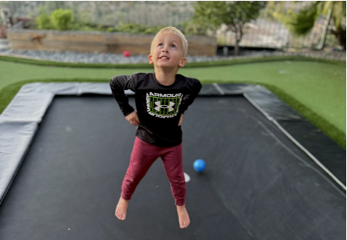 A young boy joyfully jumps on a trampoline, capturing the essence of play and childhood excitement.